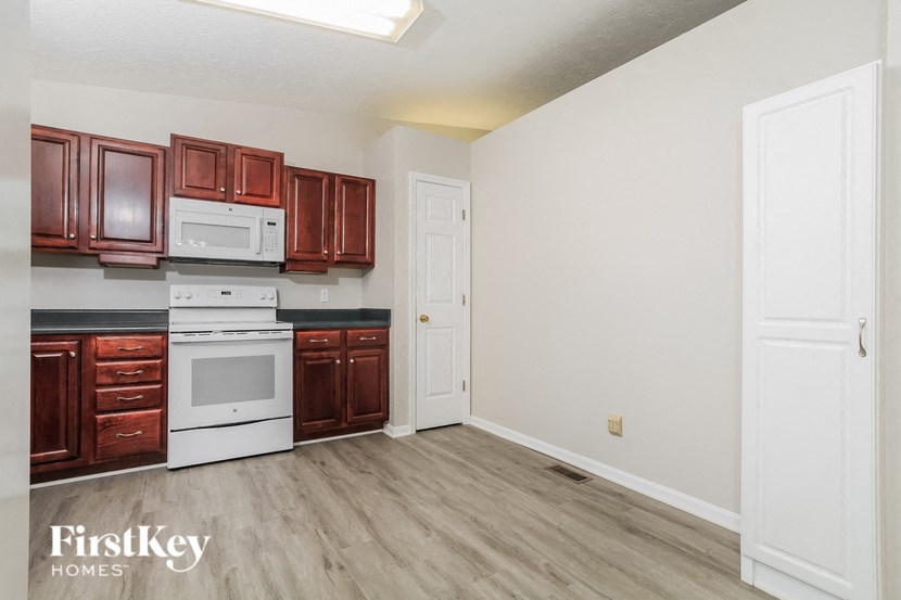 A kitchen with brown cabinets and white appliances.
