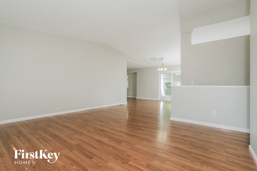 A spacious room with wooden flooring and white walls, branded with "FirstKey Homes".