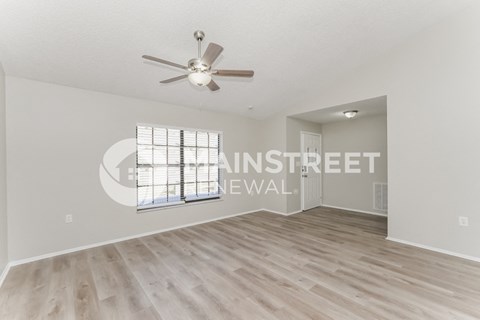 a spacious living room with hardwood floors and a ceiling fan