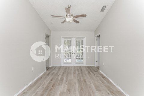 a renovated living room with hardwood flooring and white walls and a ceiling fan