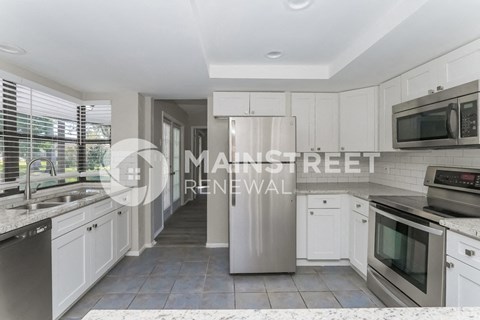 a renovated kitchen with white cabinets and stainless steel appliances