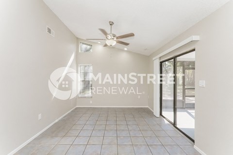 a renovated living room with a tile floor and a door to a patio
