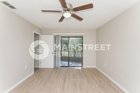a renovated living room with a ceiling fan and a sliding glass door