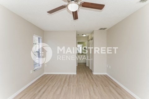 a renovated living room with a ceiling fan and a hallway