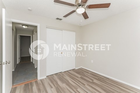 a living room with a ceiling fan and a hallway to a closet