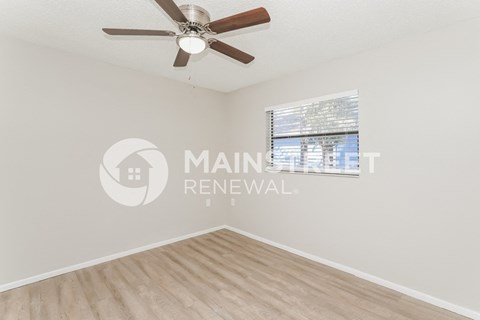 an empty living room with a ceiling fan