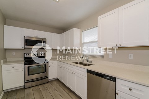 a white kitchen with white cabinets and stainless steel appliances