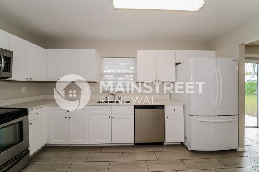 a renovated kitchen with white cabinets and stainless steel appliances