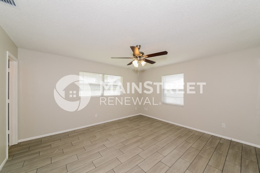 a living room with wood floors and a ceiling fan