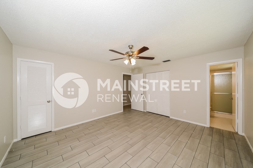 a living room with a ceiling fan and a door to a closet