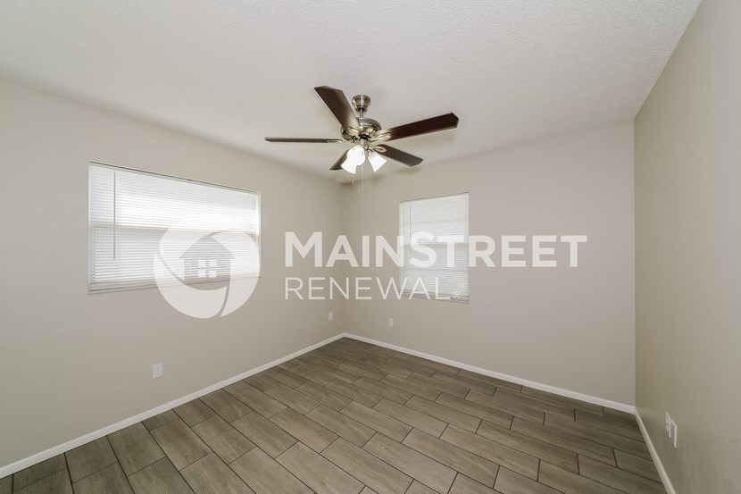 a spacious living room with wood floors and a ceiling fan
