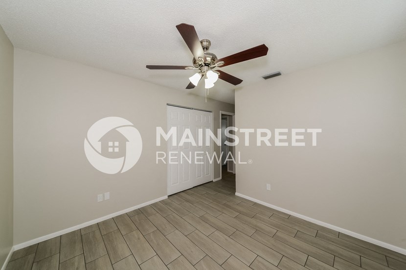 a living room with a ceiling fan and a door to a hallway