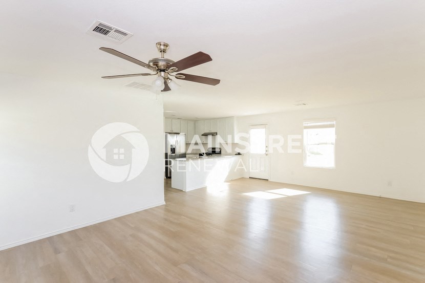 a renovated living room with white walls and a ceiling fan