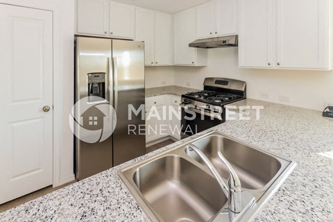 a renovated kitchen with granite counter tops and a stainless steel refrigerator