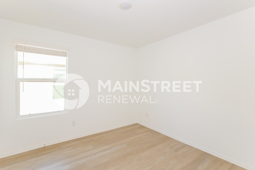 a bedroom with a large window and a wooden floor