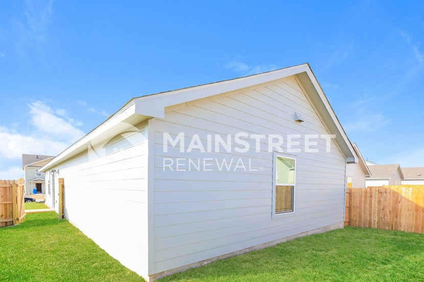 the side of a building with a lawn and a fence