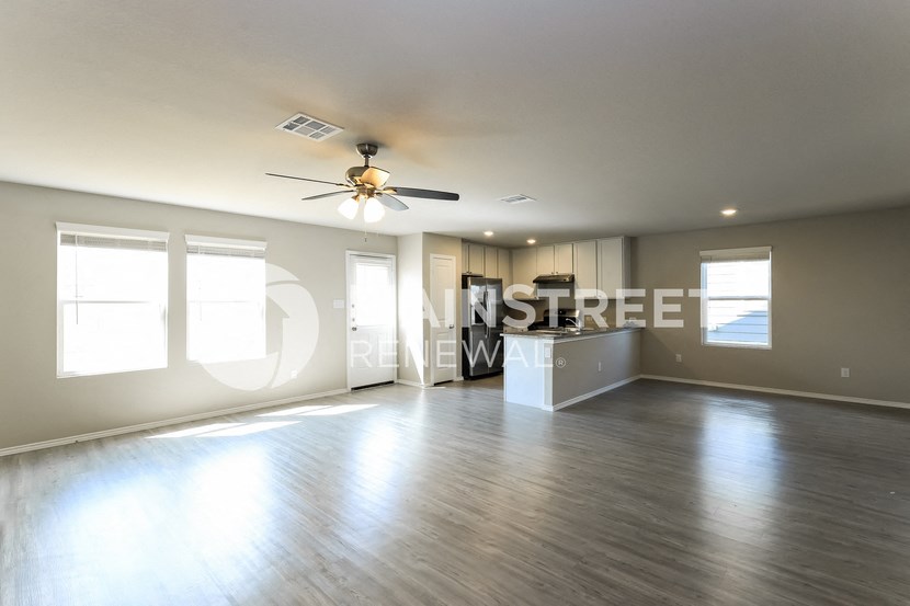 an empty living room with a ceiling fan