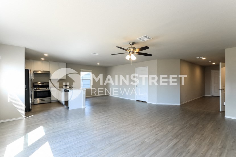 a large living room with a kitchen and a ceiling fan