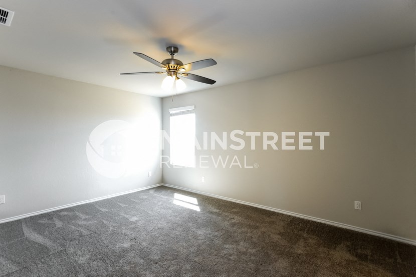 an empty living room with a ceiling fan and a window