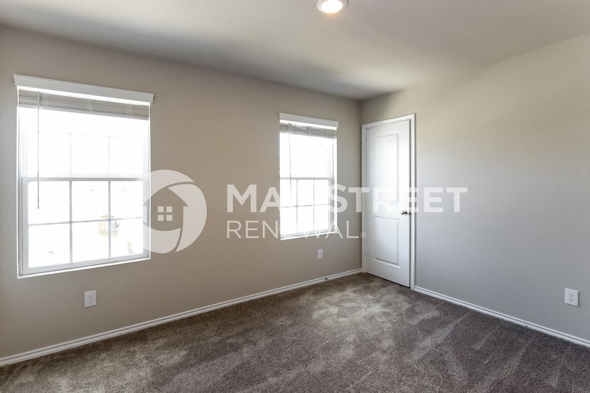 a bedroom with a carpeted floor and two windows