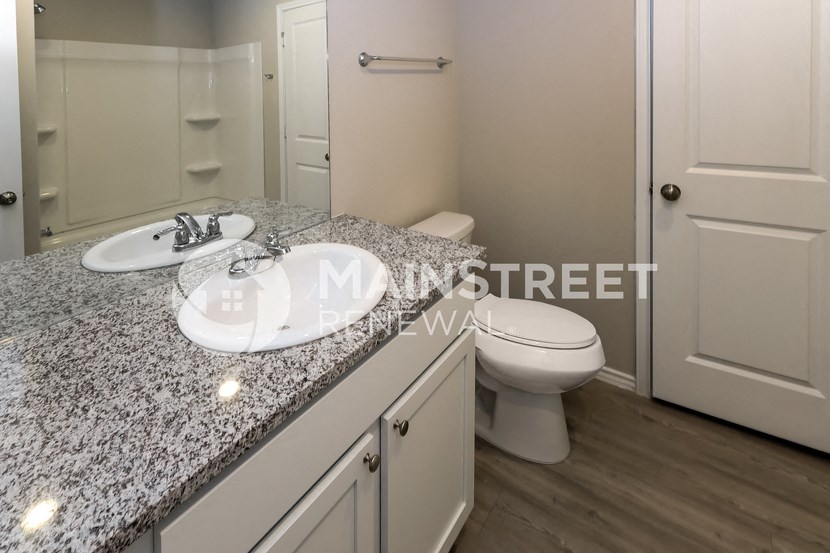 a bathroom with granite counter top and a toilet and sink