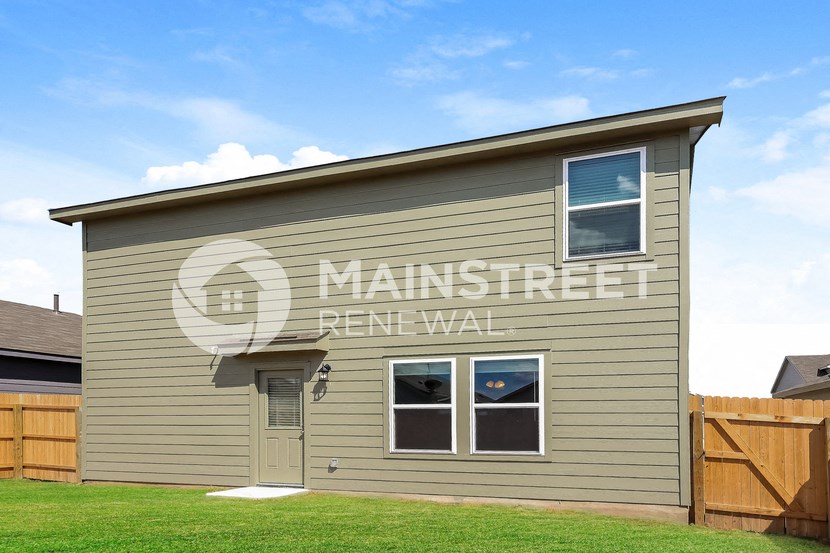 a small house with a lawn and a wooden fence