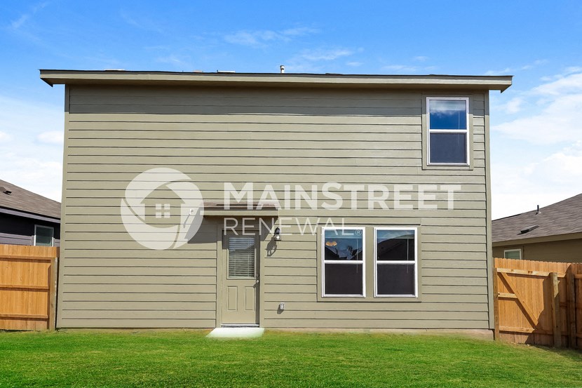 a small house with a yard in front of a wooden fence