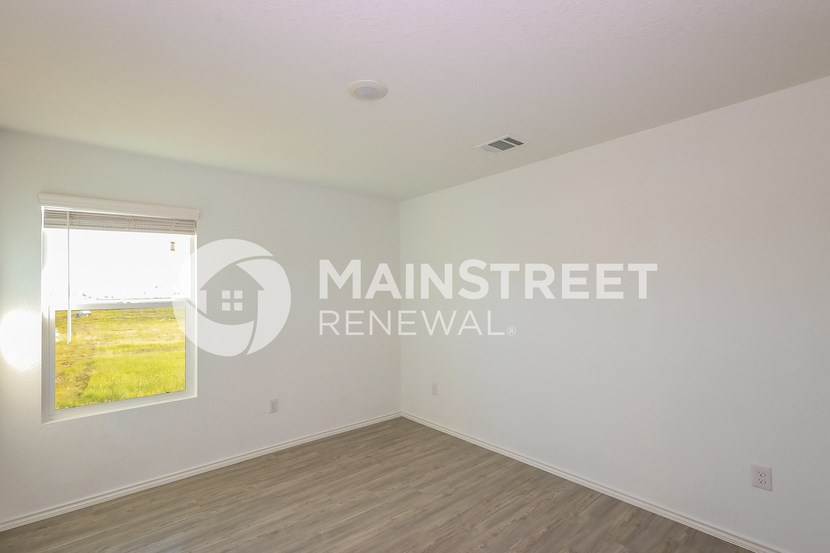 a bedroom with white walls and a window