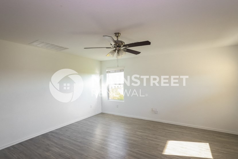 a living room with white walls and a ceiling fan