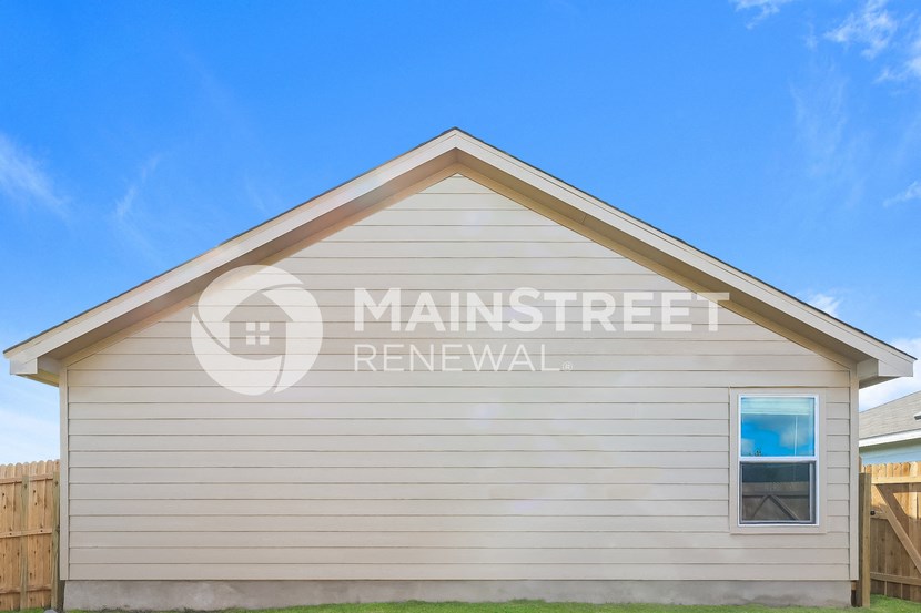 front view of a house with white siding and a wooden fence