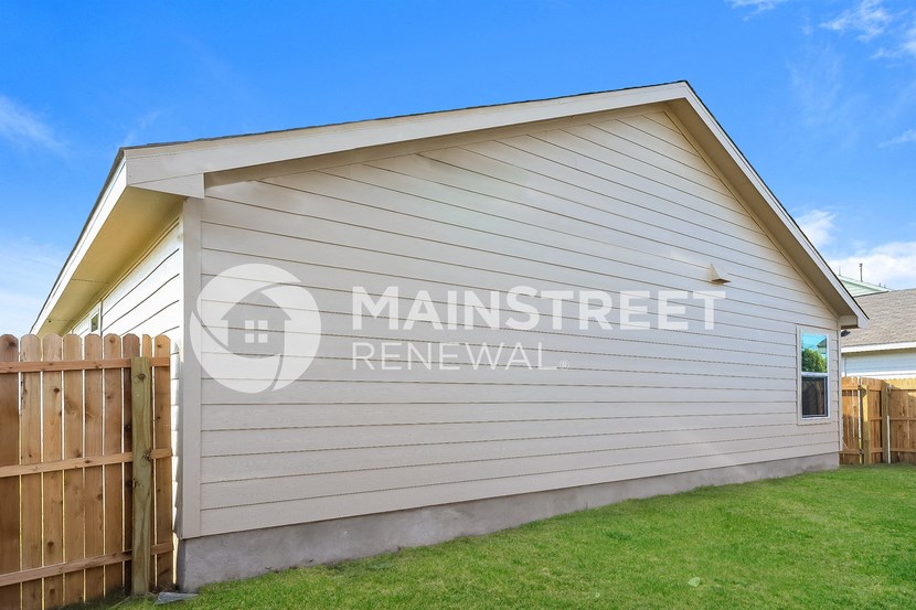 a detached garage with white siding and a wooden fence
