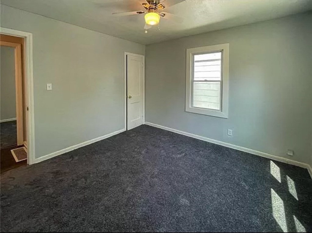 an empty room with a ceiling fan and a window