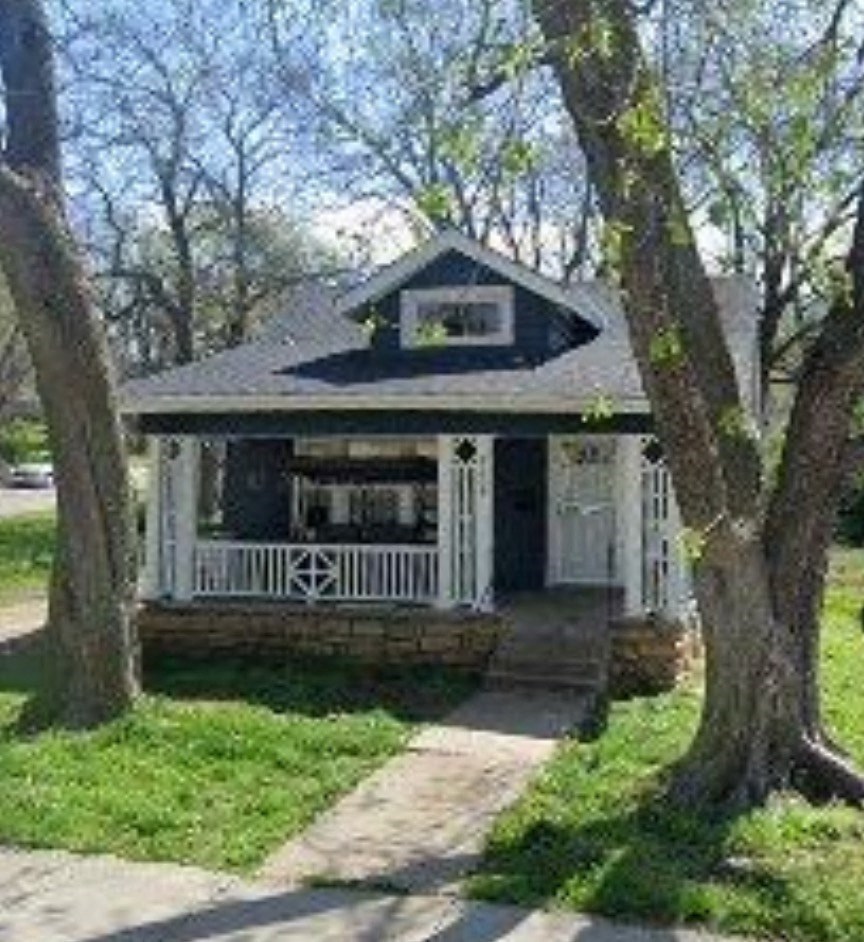 a small house with a porch and some trees