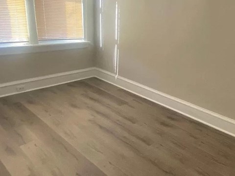 a empty room with a window and wooden floors