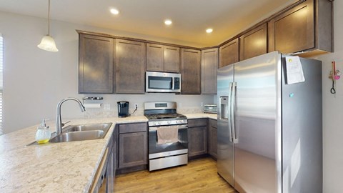 A kitchen with a refrigerator, sink, and stove.