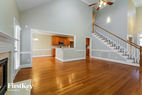 A spacious living room with wood floors and a staircase.