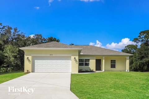 a yellow house with a lawn and a white garage door