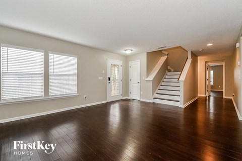 an empty living room with wood floors and a staircase