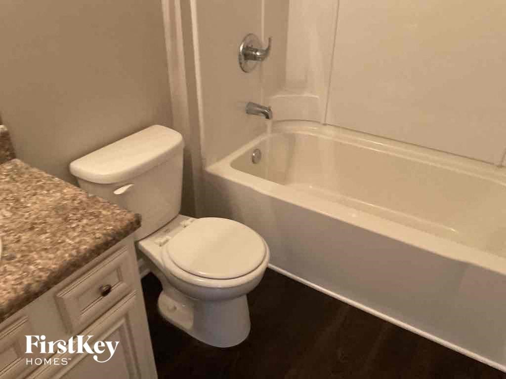 A white toilet sits next to a bathtub in a bathroom.
