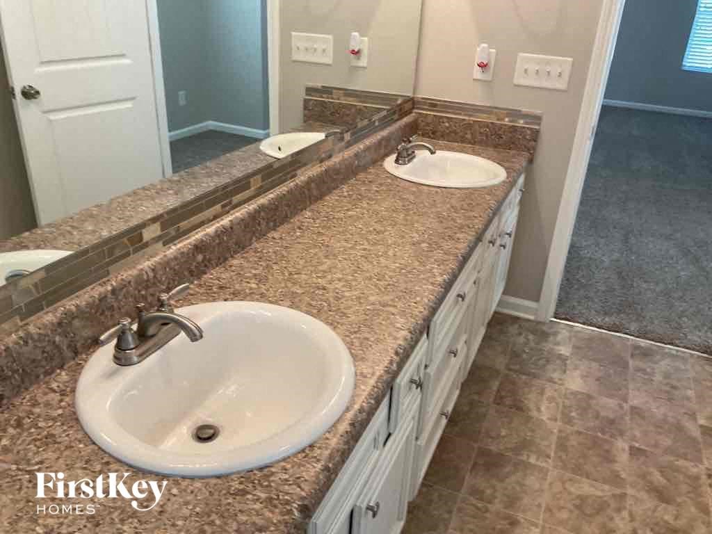 A bathroom with a granite countertop and two sinks.