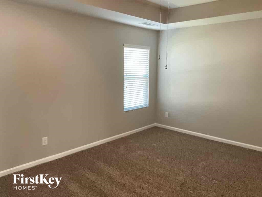 A room with a carpeted floor and a window with blinds.
