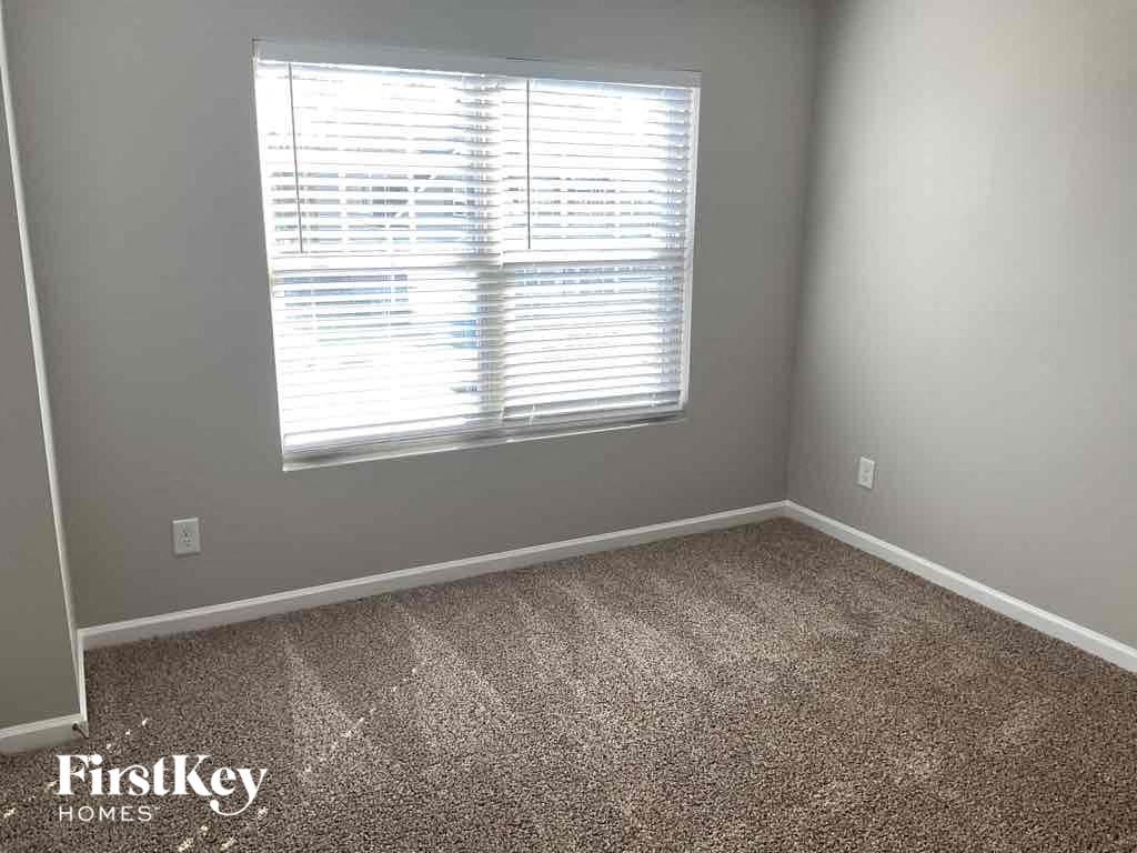 A room with a carpeted floor and a window with blinds.
