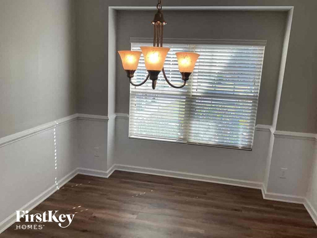 A room with a chandelier and a window with blinds.