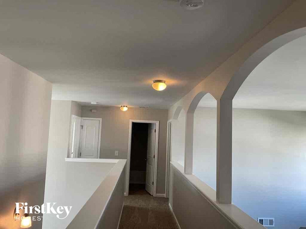 A hallway with a carpeted floor and white walls.