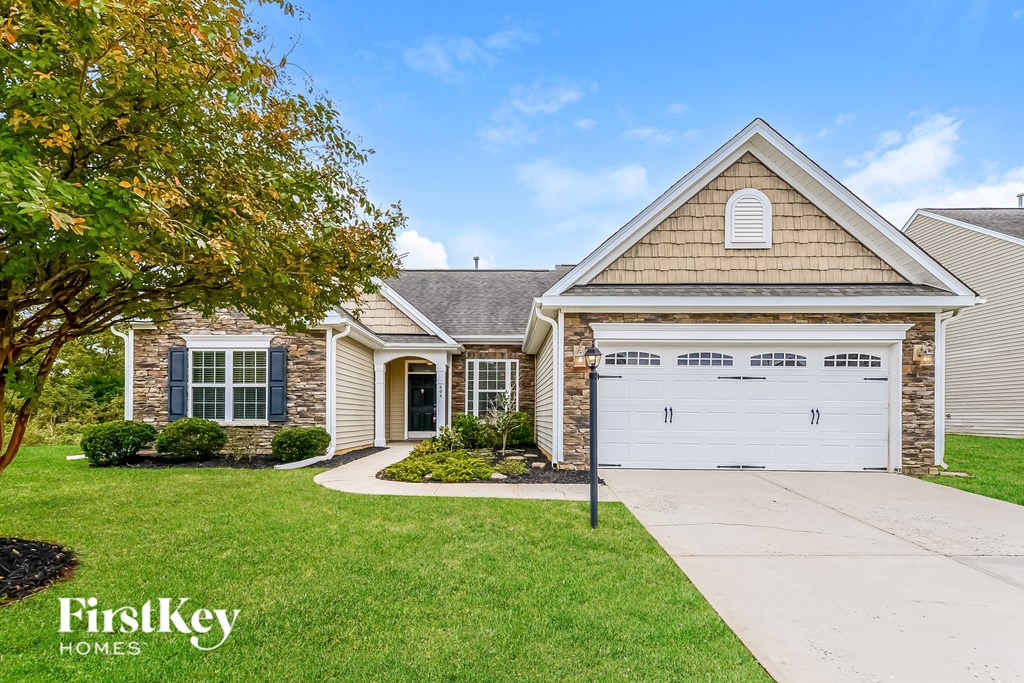 A house with a garage and a tree in front of it.