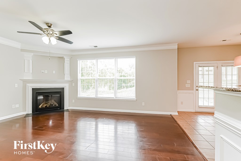 A spacious living room with a fireplace and a ceiling fan.
