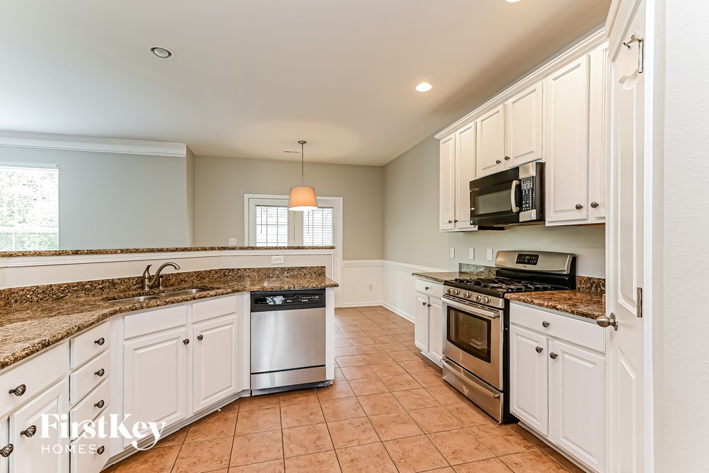 A kitchen with white cabinets and a granite countertop.