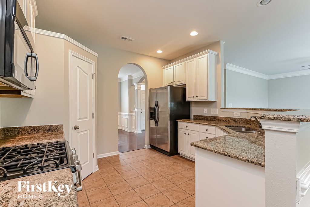 A kitchen with a granite counter top and a stove top oven.