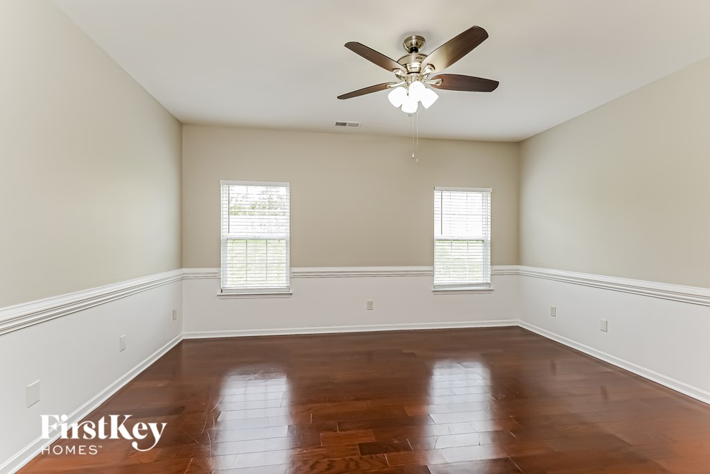 A room with a ceiling fan and two windows.