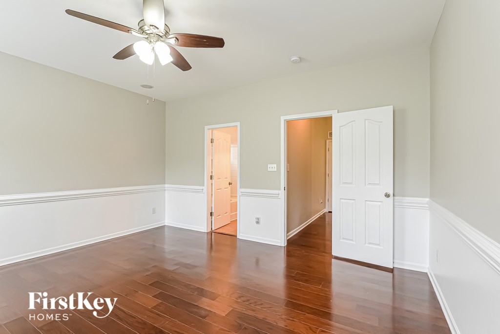 A room with a ceiling fan and wooden floors.